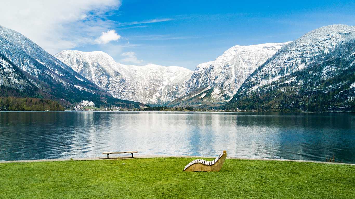 Sob a grama, vê-se um lago de água límpida e uma montanha congelada ao fundo